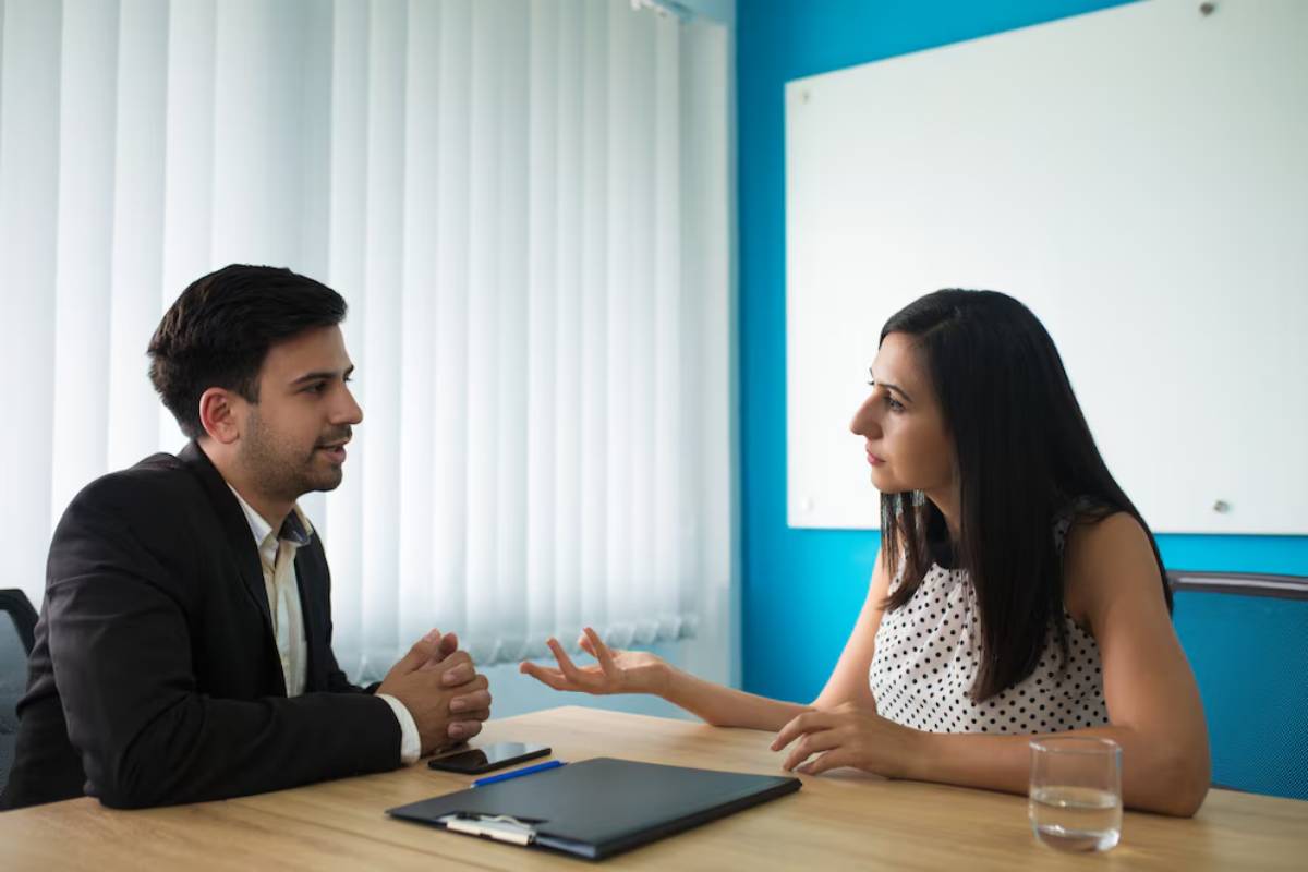 A man and a woman having a conversation in a bright office.