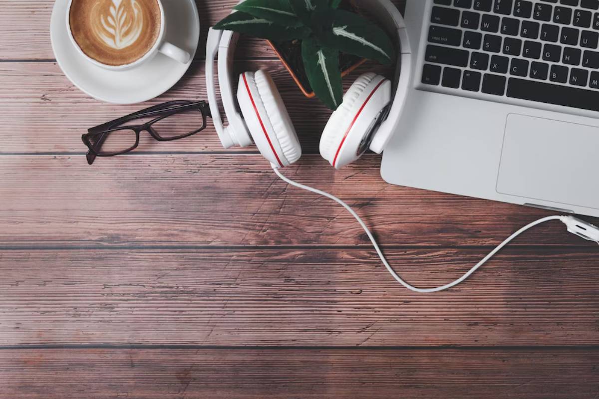 Noise-cancelling headphones on a desk next to a laptop and coffee mug