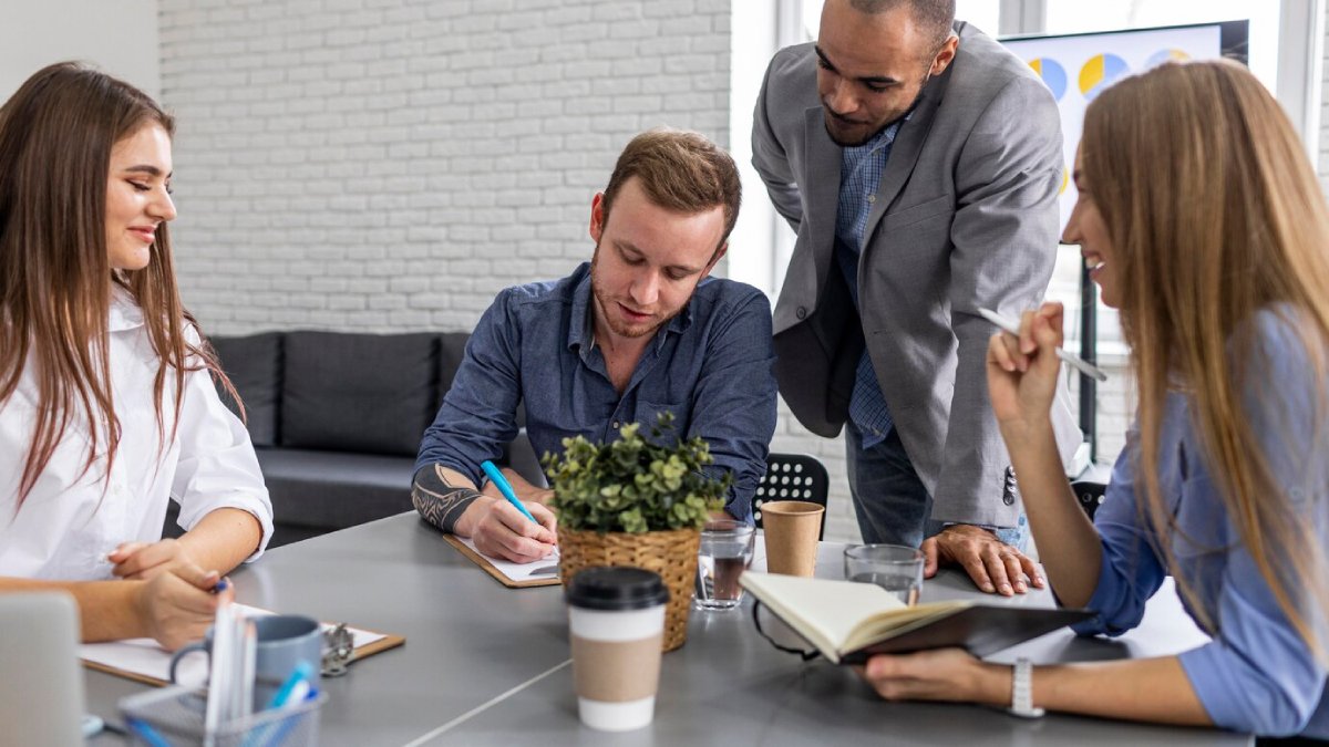 Four professionals collaborating at a table in a modern office space.