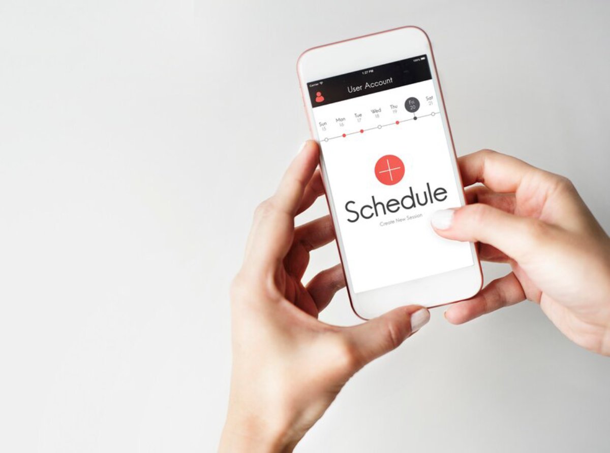 A person holding a smartphone displaying a scheduling app's user interface, featuring a calendar and the logo Schedule.