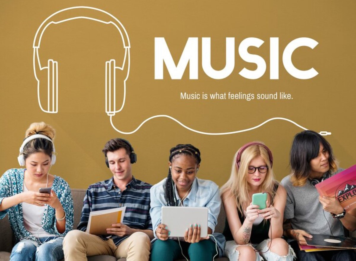 A group of six young people wearing headphones, engaged with their devices, under a 'MUSIC' mural featuring a headphone graphic.