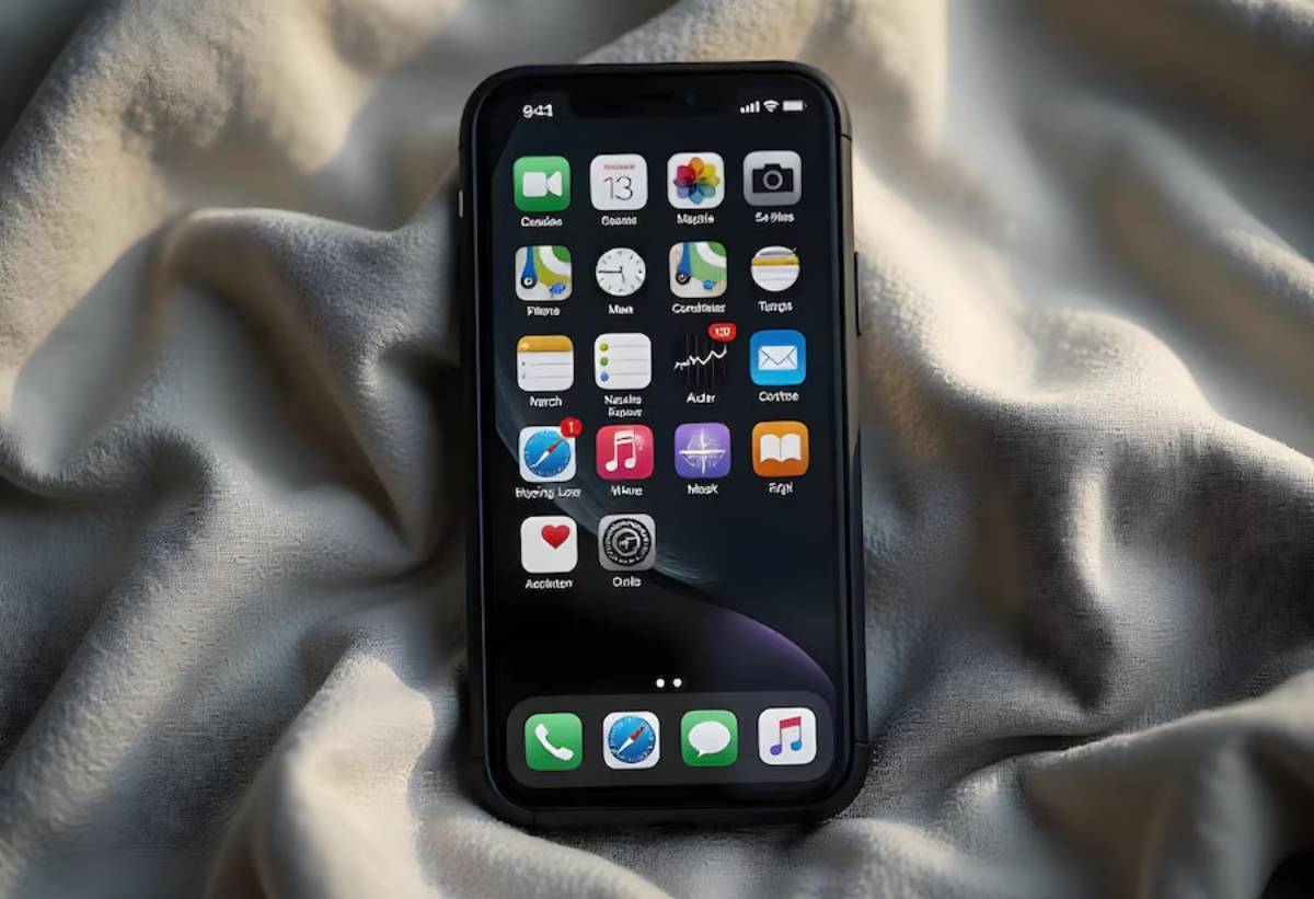 A close-up of a smartphone displaying various app icons on its home screen, resting on a soft, wrinkled fabric surface.