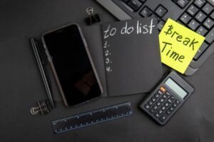 Office desk with smartphone, calculator, notebook labeled "to-do list," and a sticky note saying "Break Time."